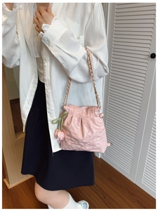 Close-up of pink quilted bucket bag with gold chain strap and decorative tulip charm