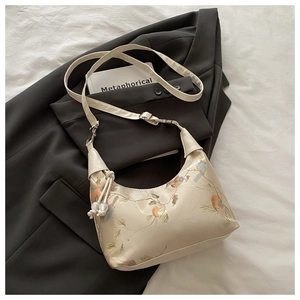 Detail view of bird and persimmon embroidery on beige faux leather shoulder bag