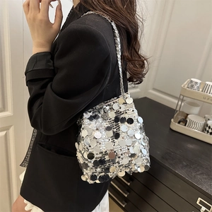 Sac seau à paillettes argentées avec bandoulière chaîne porté par un mannequin chic
