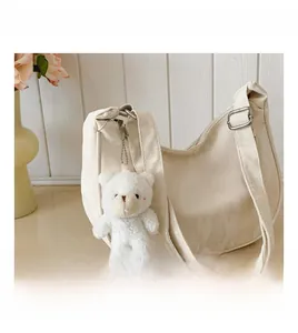 Detail of off-white nylon shoulder bag with adjustable metal buckle and teddy bear charm