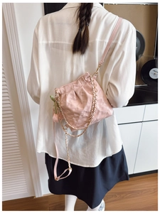 Detail of pink quilted crossbody bag with tulip charm and golden chain on model