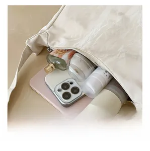 Detail view showing large interior capacity of the beige dumpling shoulder bag with essentials