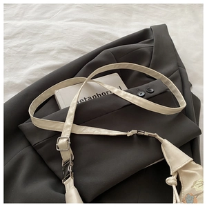 Detail of floral embroidery on off-white crossbody bag with adjustable strap and buckle