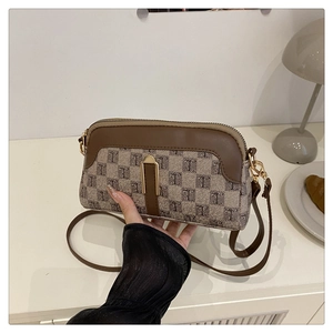 Détail d'un sac bandoulière en toile beige avec bordure en cuir marron et zip en métal