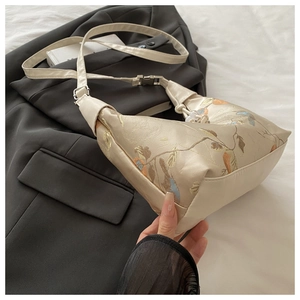 Detail of floral embroidery on cream silk shoulder bag with elegant leather strap