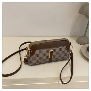 Détail du sac bandoulière en toile monogramme avec garniture en cuir brun et boucle dorée