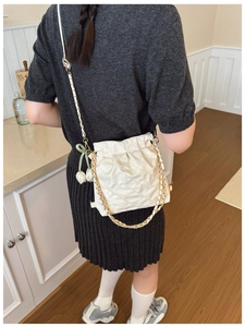 White quilted shoulder bag with gold chain and tulip floral charms on a model