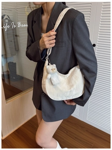 Detailed view of white dumpling bag with floral texture and cute bear charm on shoulder