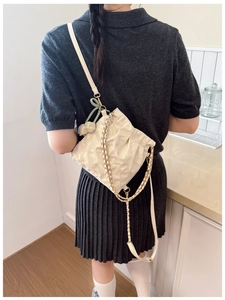 Detail view of cream quilted crossbody bag with metal chain strap and mint green bow