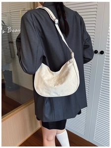 Detailed back view of a cream crescent bag with pleated texture and adjustable strap
