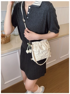 Chic white quilted bucket bag with chain strap and tulip charm shown on a model