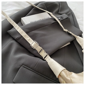 Detailed close-up of champagne satin crossbody bag with embroidery and silver buckle