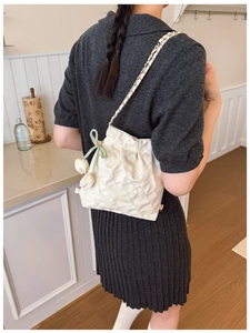 Detail of cream quilted bucket bag with gold chain strap and green tulip silk bow accessory