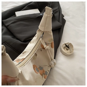 Close-up of elegant persimmon embroidery on high-quality cream satin shoulder bag