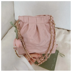 Detailed close-up of pink quilted bucket bag with chain strap and tulip charm accessory