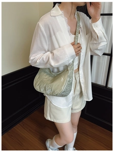 Detail view of sage green pleated pearl fabric and textured shoulder strap on bag