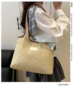 Detail of hand-woven straw tote bag with brown leather handles and decorative white label