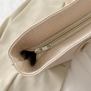 Minimalist beige crocodile embossed tote bag featuring a high-quality silver zipper closure