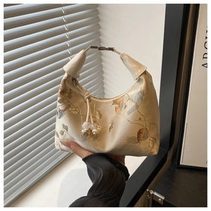 Detailed close-up of cream embroidery handbag with floral and bird gold thread patterns
