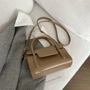 Brown retro square handbag with top handle and fashion text placed on grey suit jacket
