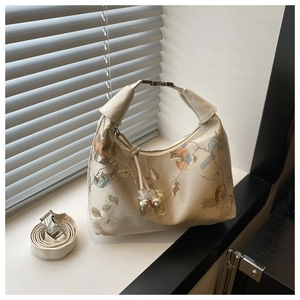 Close-up of a cream beaded handbag with floral embroidery and twisted handle detail