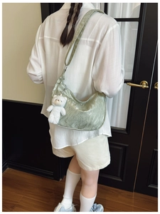 Detail of light green hobo bag with pleated texture and cute white bear charm