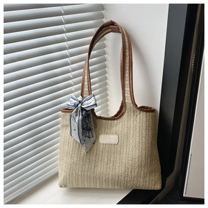 Close-up of beige woven tote with brown leather trim and a patterned decorative silk scarf
