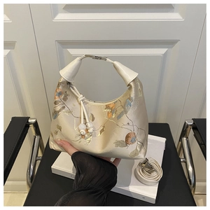 Detailed view of oriental floral embroidery on beige satin fabric with pearled charm