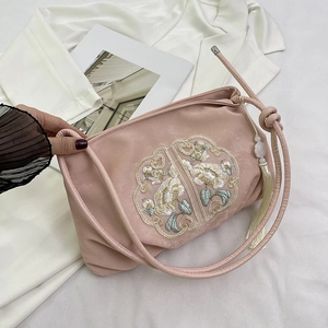 Borsa a mano in velluto rosa con ricami floreali tradizionali e nappine bianche su blazer