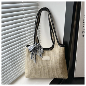 Detail of beige woven tote bag featuring black leather trim and decorative Paris print silk scarf