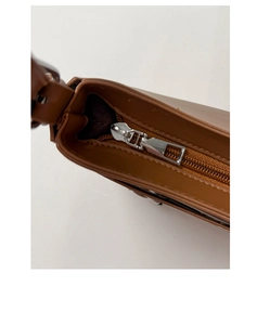 Detail of silver metal zipper and smooth brown leather on fashionable crossbody bag