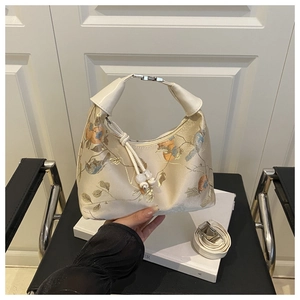 Detail view of cream handbag featuring exquisite floral and bird embroidery with bead tassels