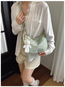 Detail of sage green dumpling bag with soft pleated texture and cute white bear charm