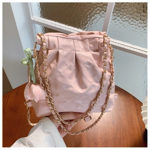 Detailed shot of pink quilted bucket bag with gold chain strap and floral charm