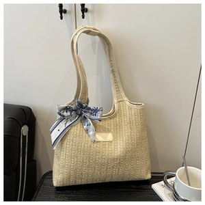 Close-up of woven straw bucket tote with cream leather trim and decorative silk scarf