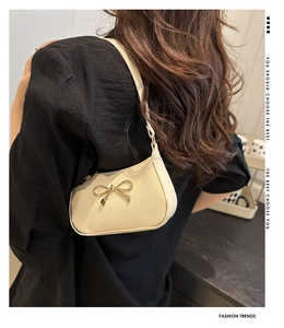 Detailed macro view of the cream lychee grain leather and golden metal bow decoration