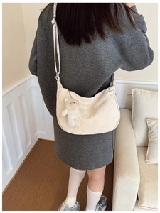 Close-up of cream crescent crossbody bag featuring a cute white teddy bear plush pendant