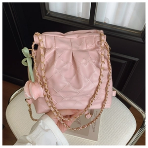 Detail of pink quilted chain bag with tulip charm and elegant gold metal shoulder strap