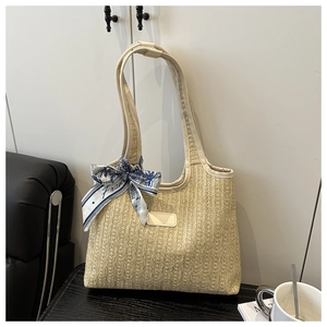 Close-up of woven straw tote bag featuring detailed texture and blue floral scarf decoration