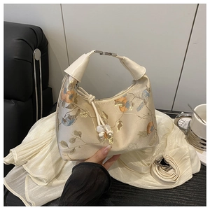 Detailed view of traditional floral embroidery on a premium gold satin shoulder bag