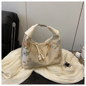 Detail of floral bird embroidery on cream silk shoulder bag with silver metal clasp