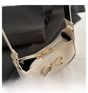 Macro shot of a smooth gold zipper on a white pebble leather shoulder bag