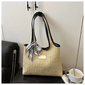 Detail of woven straw bucket tote bag with black faux leather handles and Paris scarf