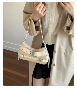 Detail of vintage cream shoulder bag with leather buckle straps and metal eyelets