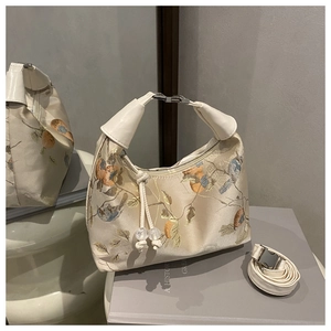 Detail of cream white embroidered hobo bag with traditional bird patterns and silver buckle