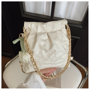 Detail of cream quilted bucket bag with gold chain strap and tulip charm decoration