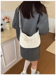 Detail of creamy white dumpling bag showing pleated fabric texture and adjustable strap