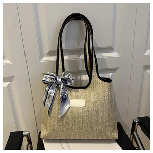 Macro shot of woven straw tote bag with black leather trim and decorative Paris scarf