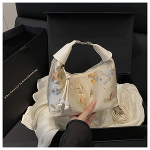 Detail of Chinese style embroidery with birds and flowers on a large off-white handbag