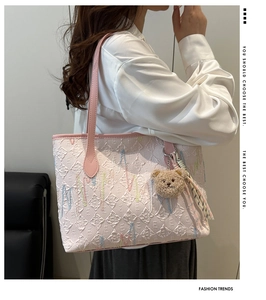 Pink quilted tote bag with stripe embroidery and teddy bear charm shown on shoulder